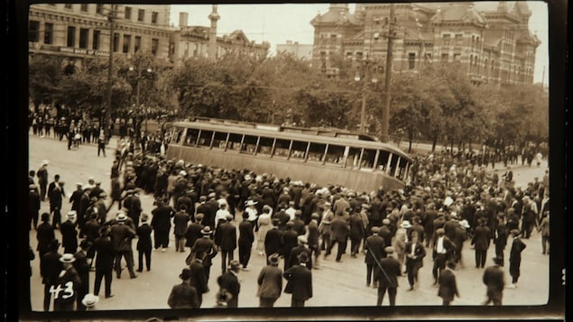 Une photo en noir et blanc d'une foule devant un tramway.