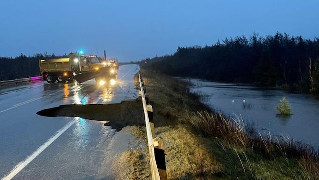 Un camion du ministère des Transport bloque la route à un endroit où les eaux ont emporté une partie de la voie.