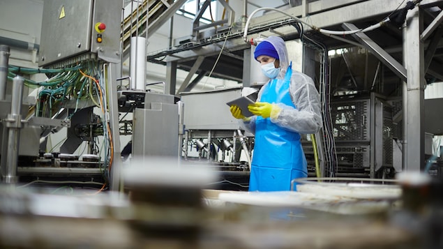 Un travailleur d'usine manipule une tablette informatique.