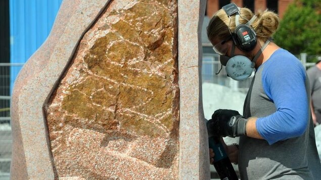 Une personne qui sculpte une pierre en granite.
