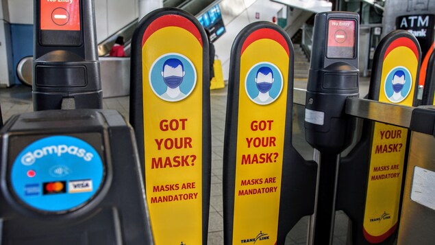 Des affiches qui rappellent que le port du masque est obligatoire sur les portiques d'entrée du Skytrain.