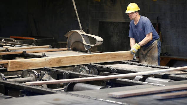 Un travailleur manie une pièce de bois dans un moulin à scie