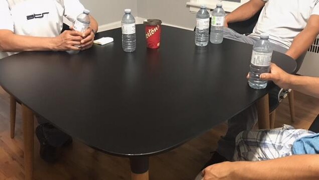 Gros plan sur une table avec des travailleurs assis autour d'une table. On ne voit pas leur visage afin de protéger leur identité. 
