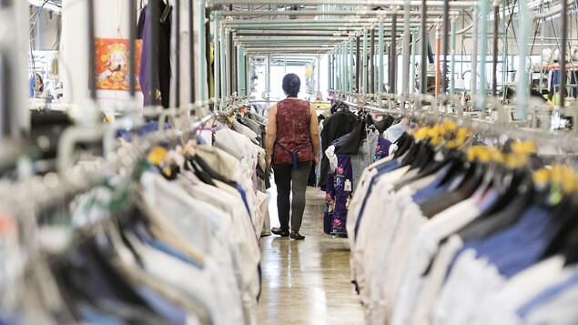 Une travailleuse marche dans une usine de vêtements à Montréal.