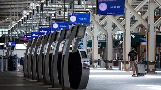 A traveller pulls luggage while walking through the U.S. departures check-in area at Vancouver International Airport, in Richmond, B.C., on July 30, 2021. The International Air Transport Association reported a 60 per cent dip in the number of passengers who flew in 2020 versus 2019. 