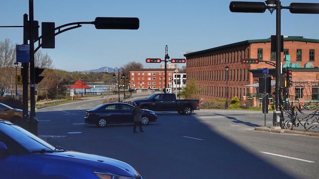Un piéton traverse la rue alors que plusieurs véhicules circulent.