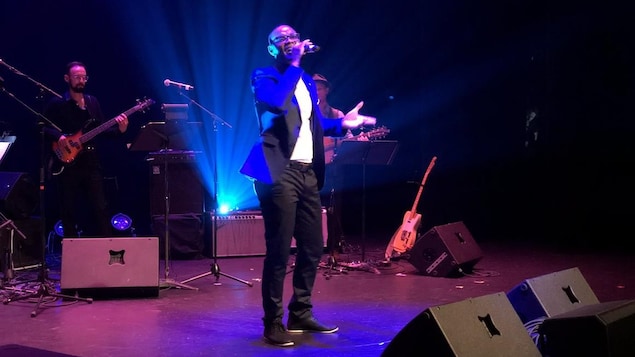 Un homme chante sur scène, un micro à la main. Un homme chante sur scène, un micro à la main.