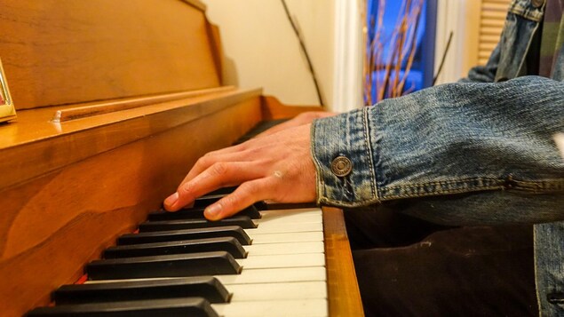 Un jeune homme photographié de manière anonyme joue du piano Un jeune homme photographié de manière anonyme joue du piano