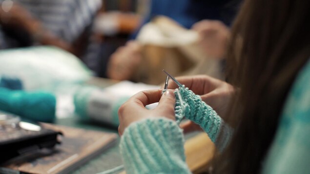 Gros plan sur les mains d'une jeune femme qui tricote. 