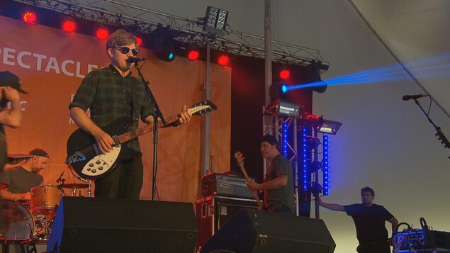 Le chanteur du groupe au micro avec sa guitare. Des musiciens jouent à l'Arrière. Le chanteur du groupe au micro avec sa guitare. Des musiciens jouent à l'Arrière.
