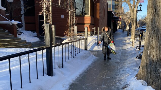 Une personne marche en hiver sur un trottoir glacé.