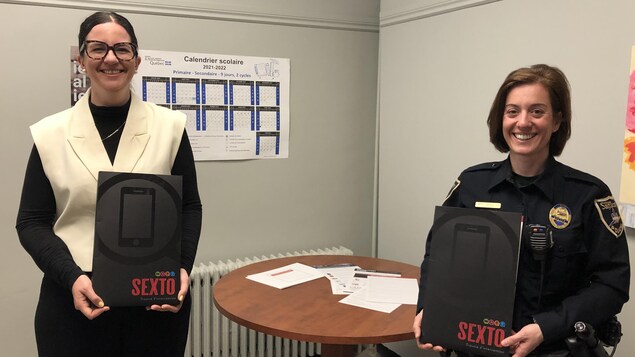 Une femme et une policière tiennent un document dans leurs mains.