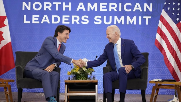 مصافحة بين الرئيس الأميركي جو بايدن (إلى اليمين) ورئيس الحكومة الكندية جوستان ترودو وهما جالسيْن.