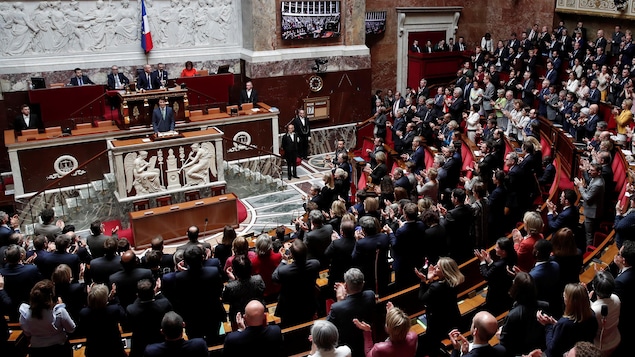 Justin Trudeau au lutrin devant des élus qui l'applaudissent. Justin Trudeau au lutrin devant des élus qui l'applaudissent.