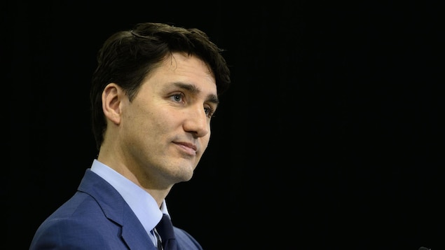 Justin Trudeau tient un micro tout en fixant des yeux.