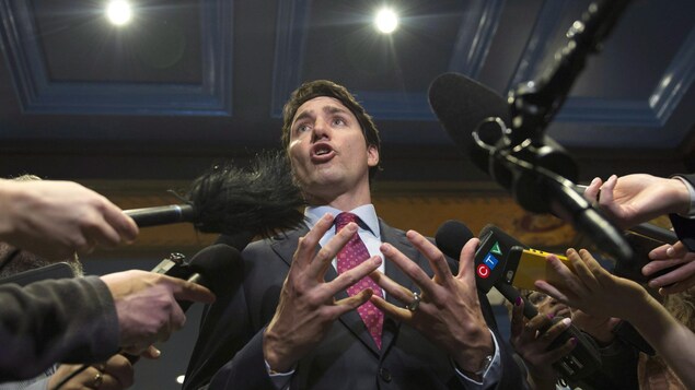 Le premier ministre Trudeau entouré de journalistes qui lui tendent leur micro.