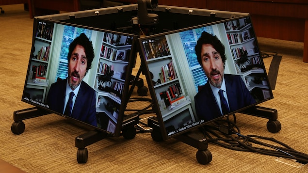 Gros plan de Justin Trudeau en vidéoconférence sur deux écrans d'ordinateurs.