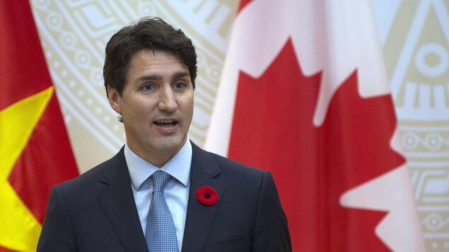 Le premier ministre canadien Justin Trudeau devant les drapeaux du Vietnam et du Canada.
