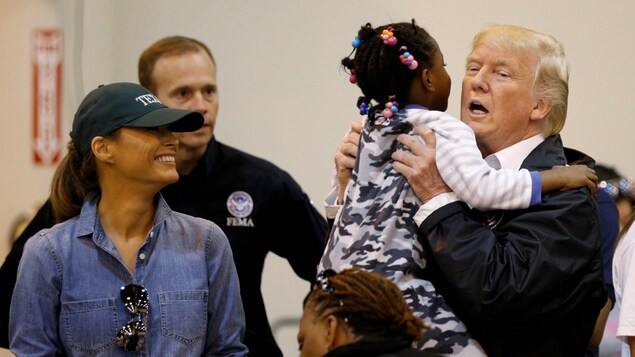Melania Trump sourit en regardant Donald Trump prendre une fillette dans ses bras, dans un centre de sinistrés de Houston, au Texas.