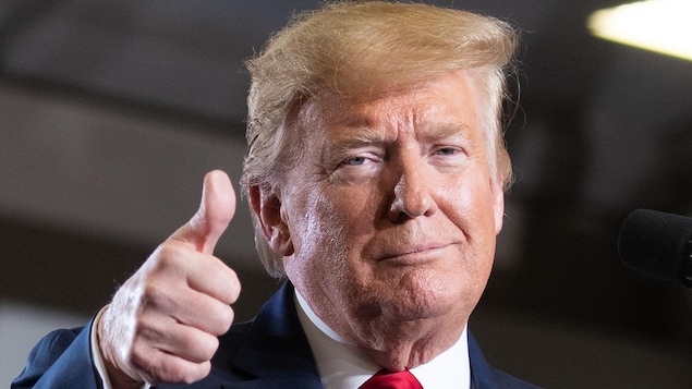 Gros plan du président Trump, qui regarde la caméra en levant le pouce.
