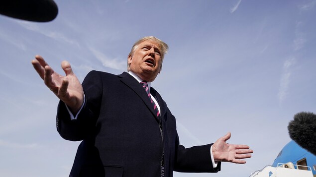 Le président Trump, les bras ouverts, dehors, tout près de l'avion présidentiel.
