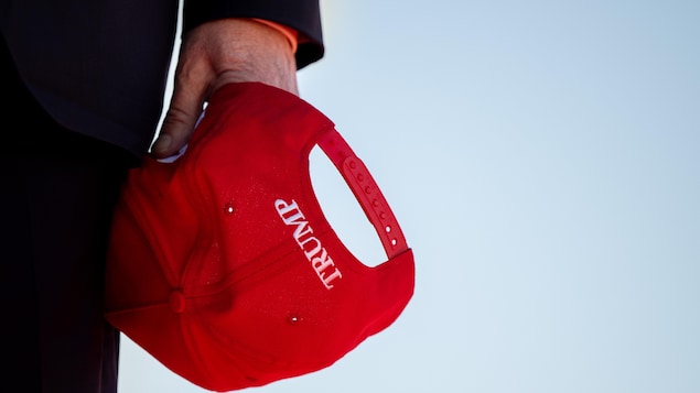 Gros plan sur une casquette MAGA sur laquelle il est écrit Trump, dans la main de Donald Trump.