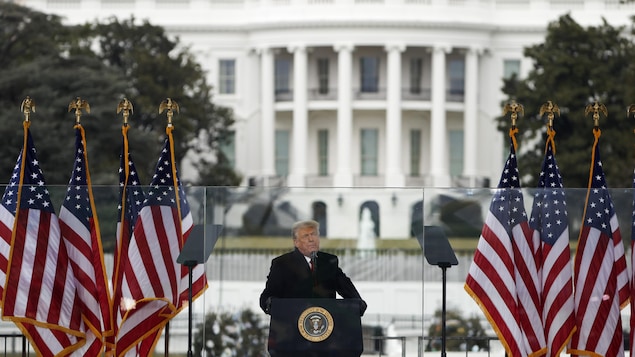 Donald Trump debout derrière un lutrin.