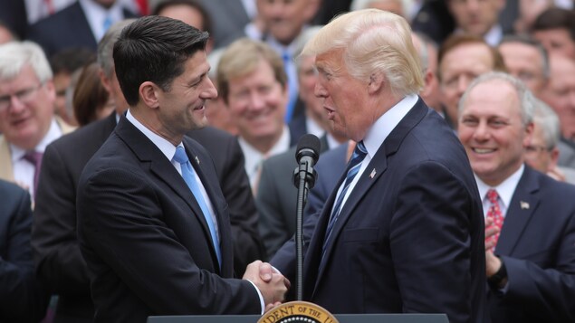 Le président des États-Unis, Donald Trump, sert la main de Paul Ryan, président de la Chambre des représentants, après l'adoption du projet de loi qui remplacera l'Obamacare.