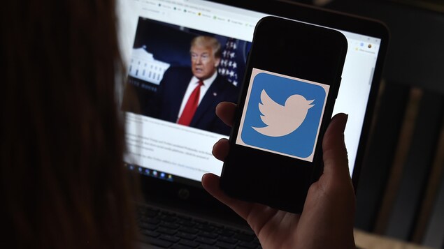 Dans cette illustration photographique, un logo Twitter est affiché sur un téléphone portable avec la page Twitter du président Trump en arrière-plan.