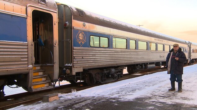 Un homme fume une cigarette à côté du train
