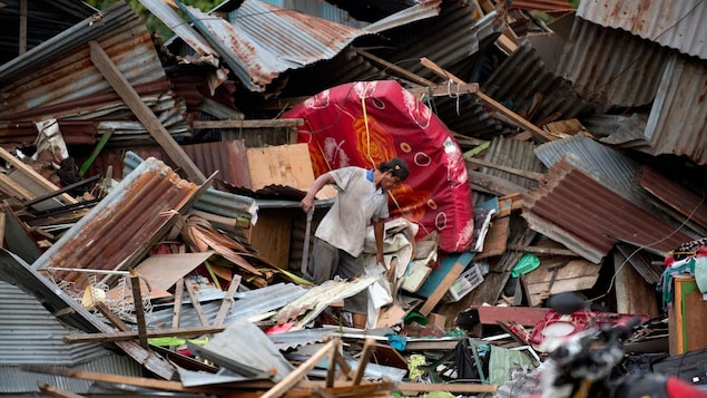 Un homme cherche ses biens dans les débris de sa maison détruite par les tremblements de terre et la tsunami à Palu.