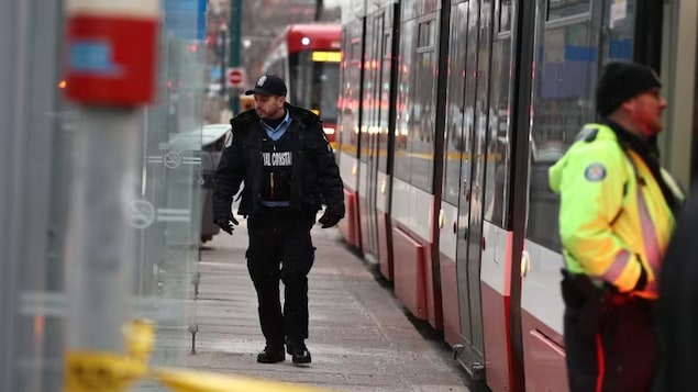 A TTC special constable walks alongside a streetcar where a woman in her 20s was stabbed several times on Tuesday. A suspect was arrested and the victim taken to hospital with serious but non-life-threatening injuries. (Evan Mitsui/CBC)