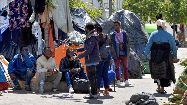 Un groupe d'hommes près d'un campement dans la rue