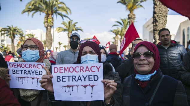 Des manifestantes dans les rues de Tunis portent des pancartes sur lesquelles est écrit : la démocratie trahie
