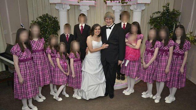 La famille Turpin pose, les filles sont habillées en robe à carreaux et les garçons en habit.