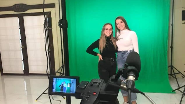Deux adolescentes se tiennent debout devant une caméra.