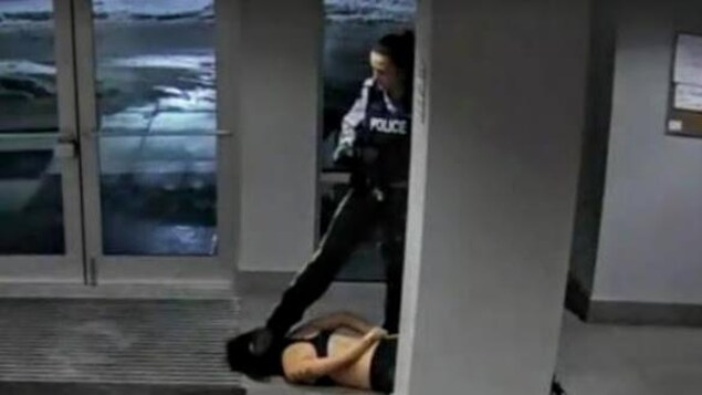 Arrêt sur image d'une vidéo montrant une agente de la GRC qui appuie son pied sur la tête d'une jeune femme allongée au sol.