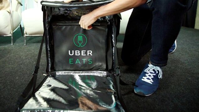 Un chauffeur d'Uber Eats se prépare à livrer un repas, en ouvrant son sac de livraison.