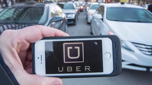 Un téléphone avec le logo d'Uber devant des voitures dans la circulation.