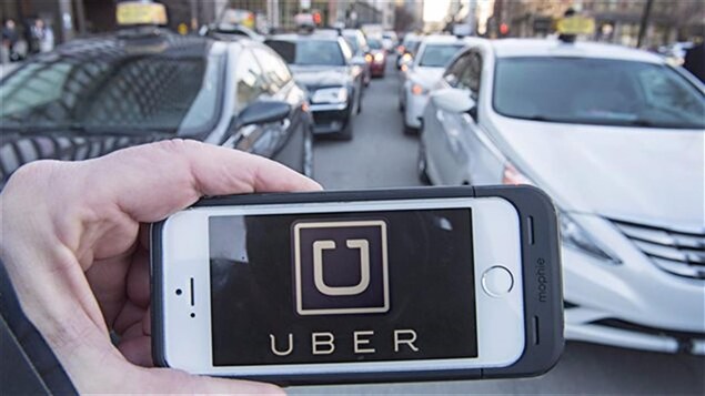 Un homme tient un téléphone intelligent avec l'application d'Uber devant des voitures de taxi. Un homme tient un téléphone intelligent avec l'application d'Uber devant des voitures de taxi.
