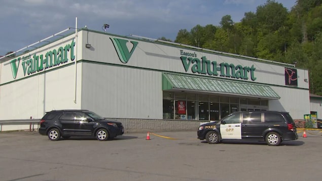 Un véhicule de la Police provinciale de l'Ontario et une voiture devant une épicerie.