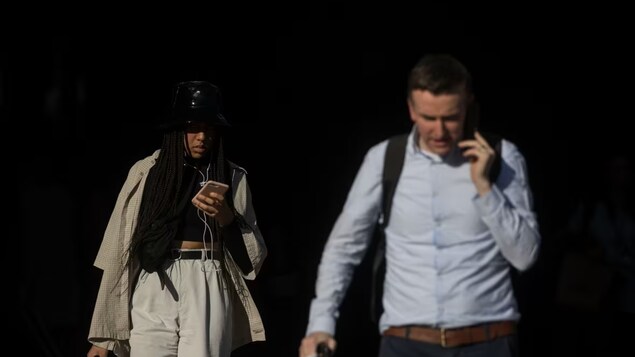 Commuters use their mobile phones near St. Pancras International railway station in London in February 2019. Europeans are protected from high roaming rates, but that's not the case for Canadians. (Simon Dawson/Bloomberg)