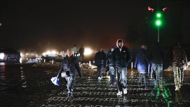 Des civils marchent dans une rue non éclairée après les frappes de missiles d'hier à Kiev.