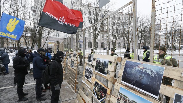 Des manifestants ukrainiens sont debout devant des affiches montrant le conflit en Crimée. Des manifestants ukrainiens sont debout devant des affiches montrant le conflit en Crimée.