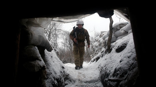 Un soldat marche le long d'une tranchée couverte de neige.