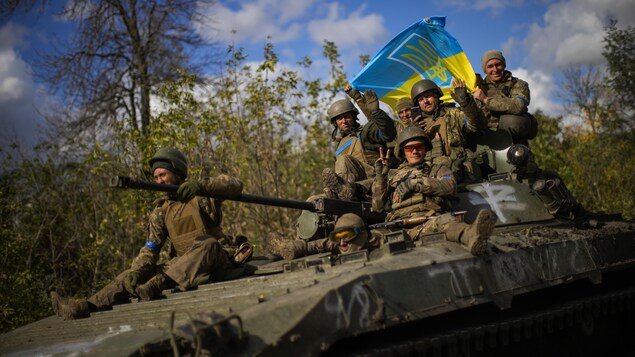 Des soldats ukrainiens sont assis sur un véhicule blindé.