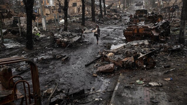 Una mujer camina entre tanques rusos destruidos en Bucha, cerca de Kiev, el domingo.