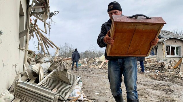 Un habitant se promène parmi les décombres de bâtiments résidentiels détruits par un tir de missile russe, près de la ville de Zolochiv, dans la région de Lviv le 9 mars 2023.