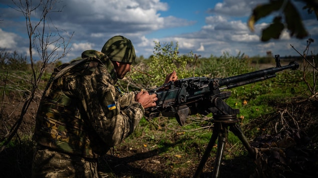 Un soldat ukrainien se tient derrière une mitrailleuse.
