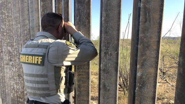 Un policier observe à travers la clôture qui sépare les États-Unis du Mexique